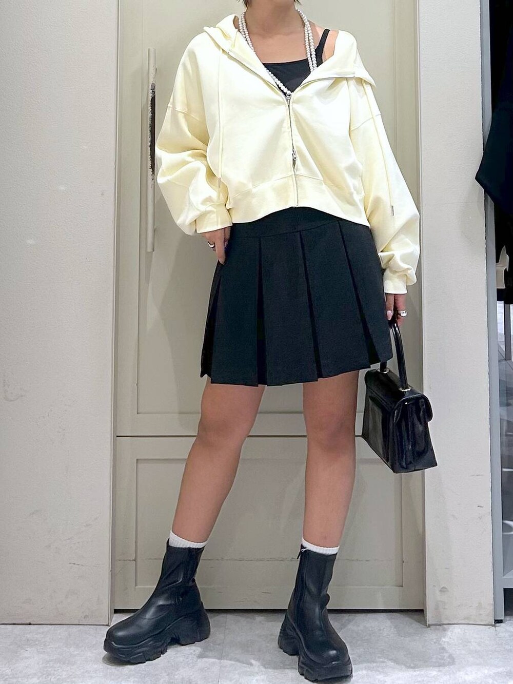 ブラック系のブーツ、ブラック系のボストンバッグ、グレー系のスカートを着用したレディースの秋コーディネートの4枚目の写真