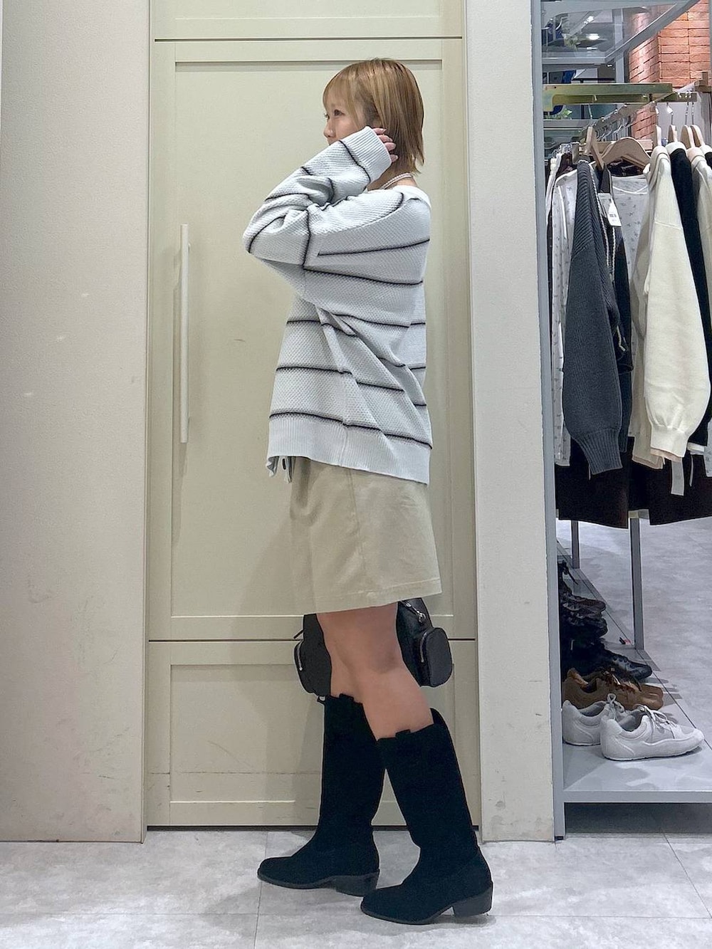 ホワイト系のキャミソール、ブラック系のブーツ、ブラック系のボストンバッグを着用したレディースの春コーディネートの2枚目の写真