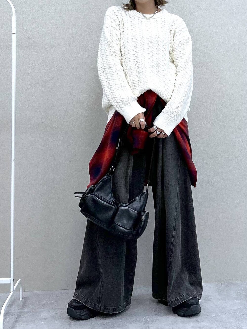 ブラック系のスニーカー、ブラック系のデニムパンツ、ブラック系のショルダーバッグを着用したレディースの冬コーディネートの4枚目の写真