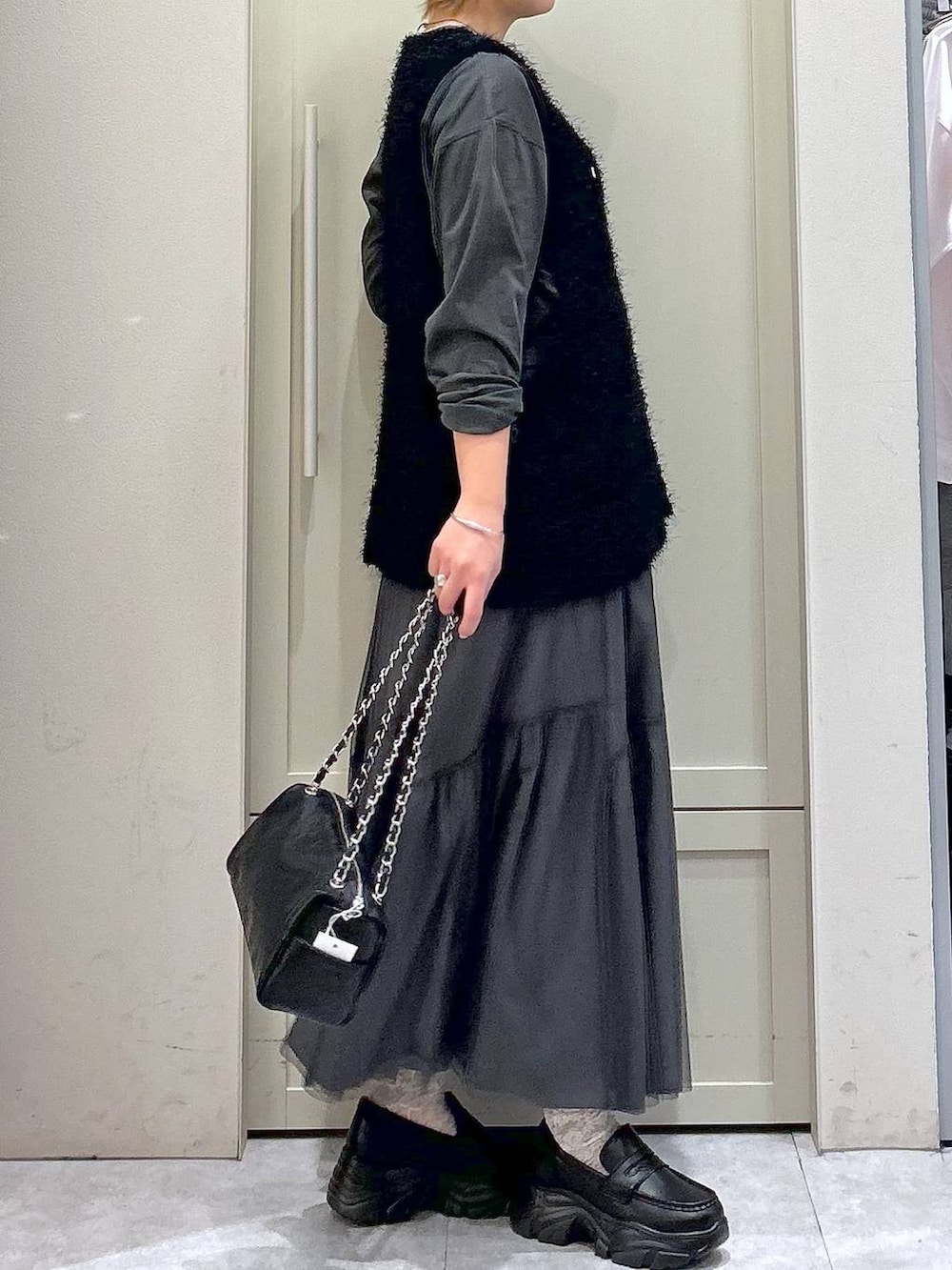 ブラック系のショルダーバッグ、ブラック系のローファー、ブラック系のベストを着用したレディースの春コーディネートの5枚目の写真