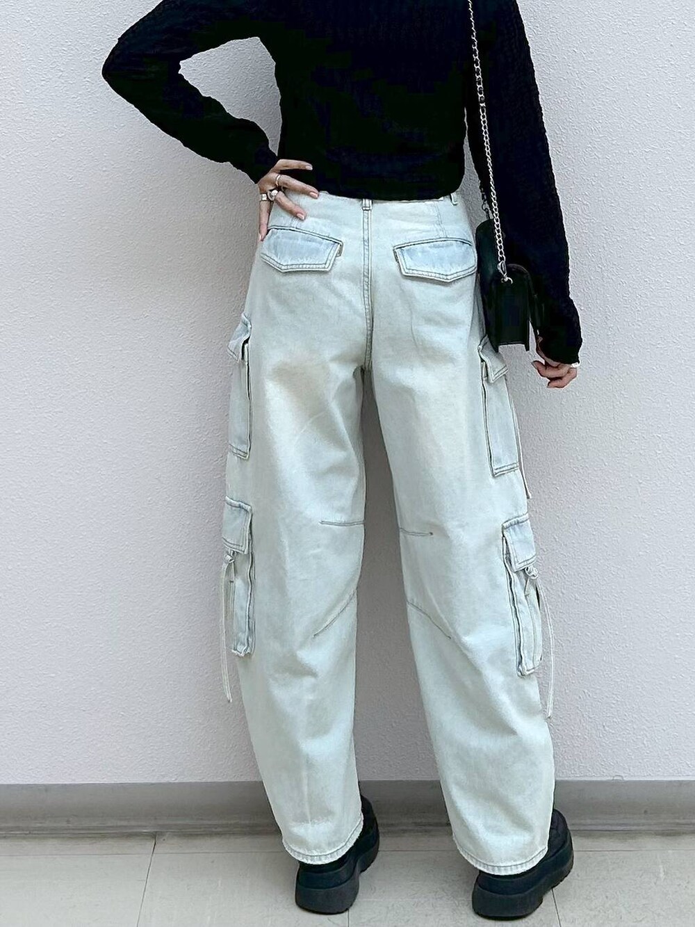 ブラック系のブーツ、ブルー系のデニムパンツ、ブラック系のショルダーバッグを着用したレディースの秋コーディネートの5枚目の写真