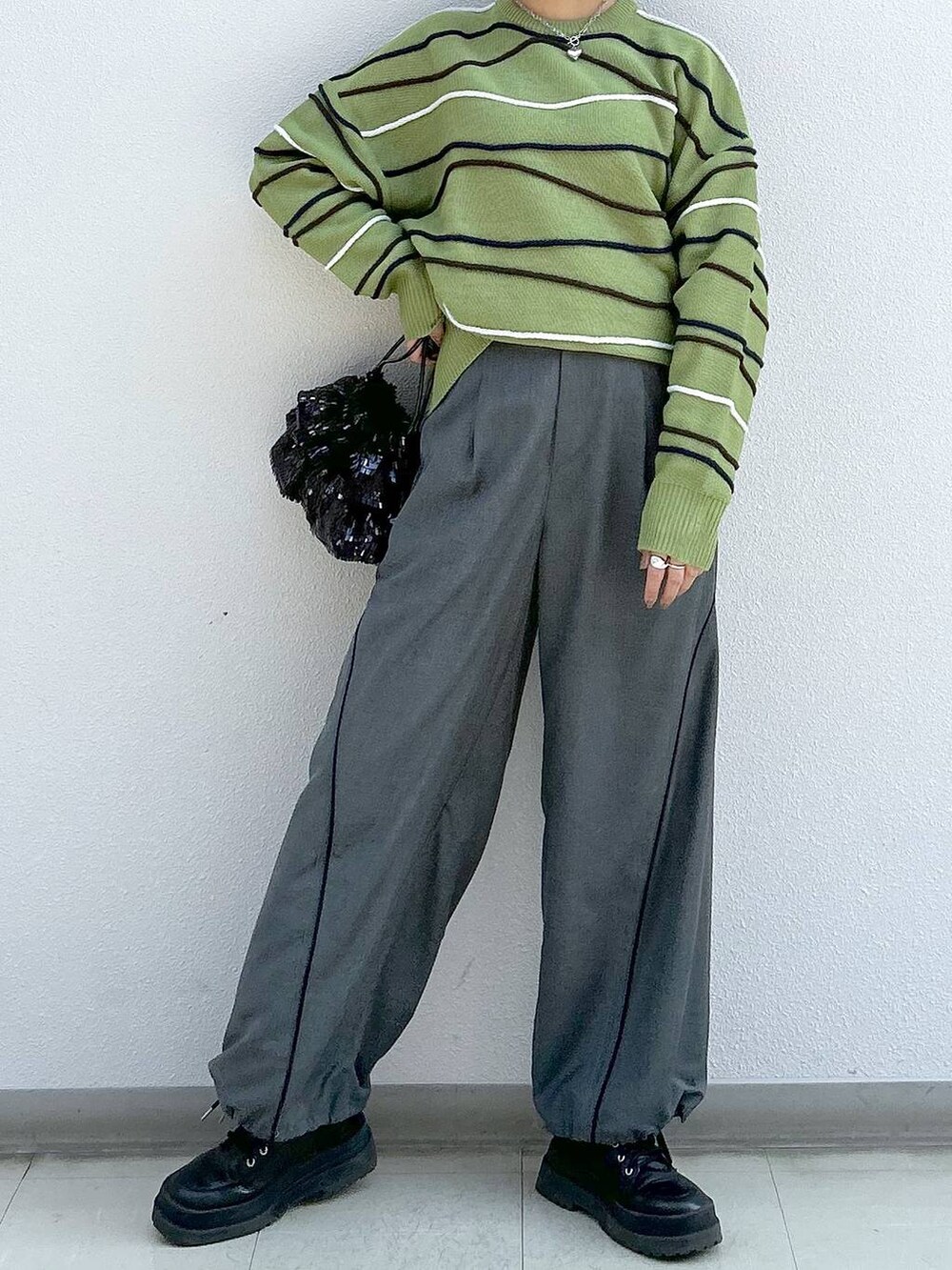 グレー系のその他パンツ、ブラック系のブーツ、グリーン系のニット/セーターを着用したレディースの冬コーディネートの4枚目の写真