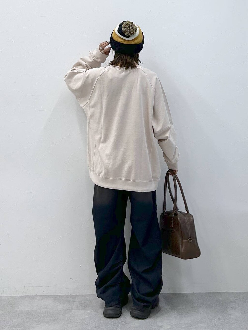 ブラック系のスニーカー、ブルー系のデニムパンツ、ブラウン系のボストンバッグを着用したレディースの冬コーディネートの3枚目の写真