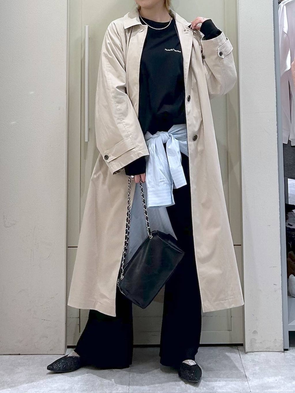ブラック系のショルダーバッグ、ブラック系のパンプス、ベージュ系のステンカラーコートを着用したレディースの春コーディネートの4枚目の写真