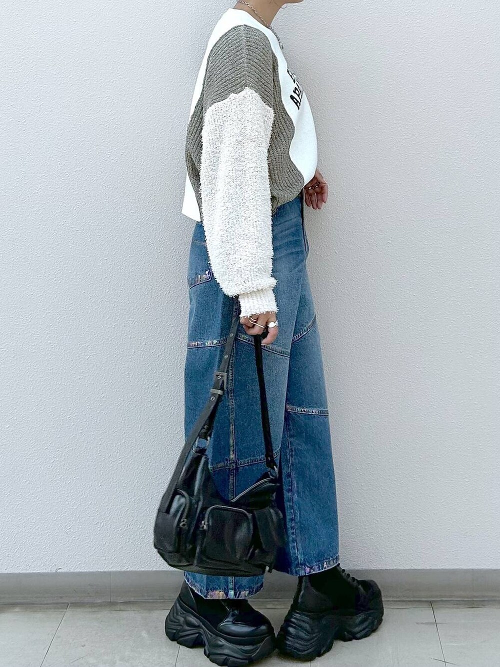 ブラック系のスニーカー、ブラック系のショルダーバッグ、ブルー系のデニムパンツを着用したレディースの冬コーディネートの5枚目の写真