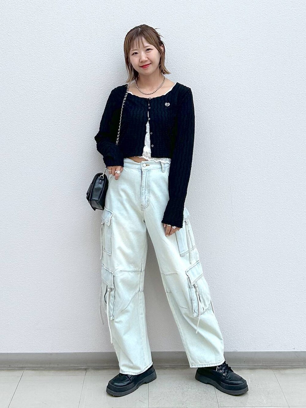 ブラック系のブーツ、ブルー系のデニムパンツ、ブラック系のショルダーバッグを着用したレディースの秋コーディネートの6枚目の写真