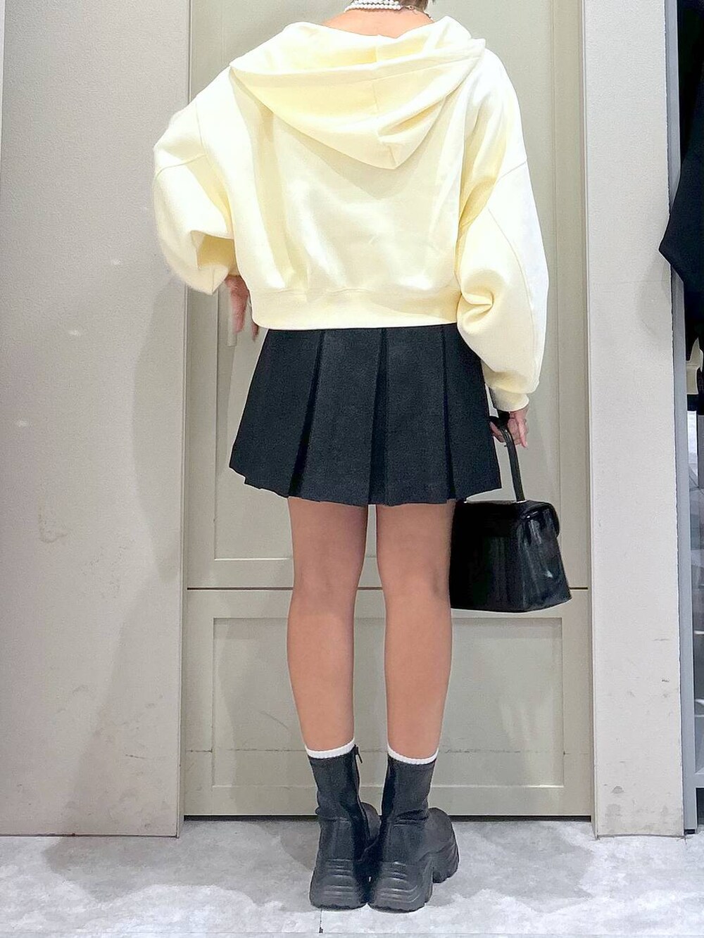 ブラック系のブーツ、ブラック系のボストンバッグ、グレー系のスカートを着用したレディースの秋コーディネートの6枚目の写真