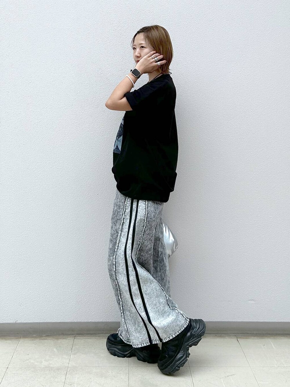 ブラック系のスニーカー、グレー系のデニムパンツ、シルバー系のショルダーバッグを着用したレディースの夏コーディネートの2枚目の写真