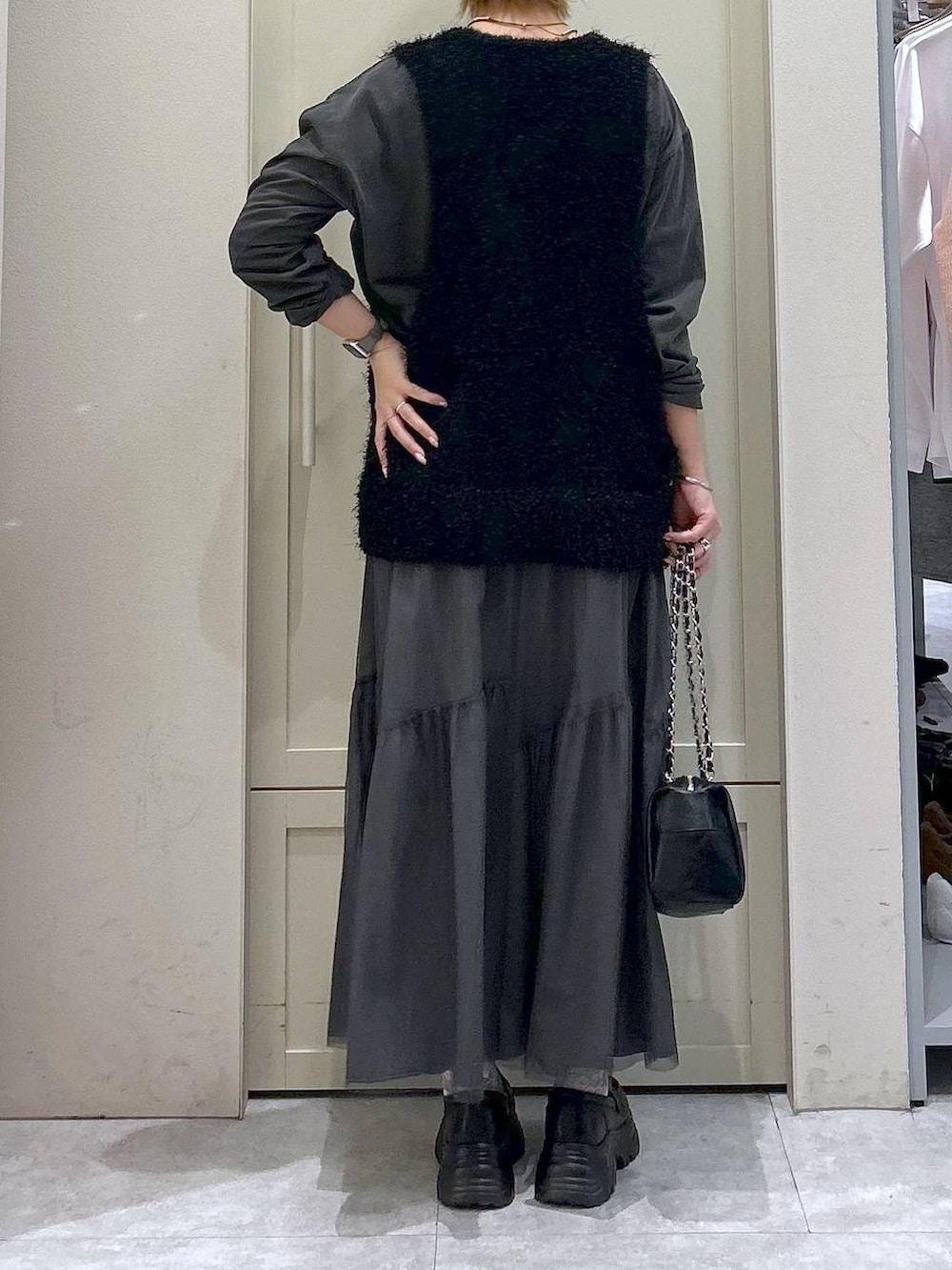 ブラック系のショルダーバッグ、ブラック系のローファー、ブラック系のベストを着用したレディースの春コーディネートの6枚目の写真