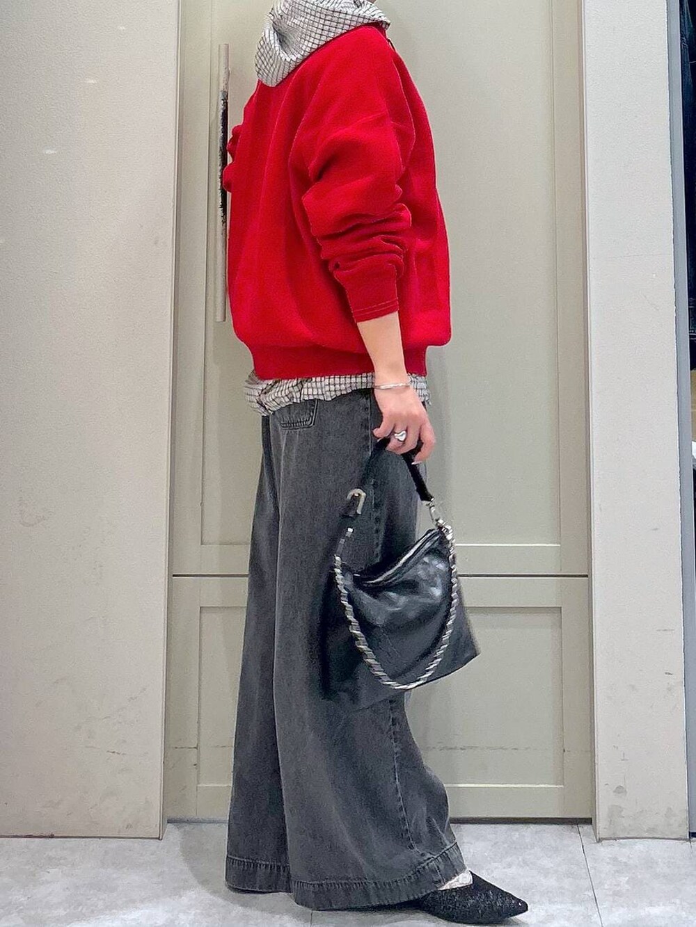 ブラック系のデニムパンツ、レッド系のニット/セーター、ブラック系のショルダーバッグを着用したレディースの春コーディネートの5枚目の写真