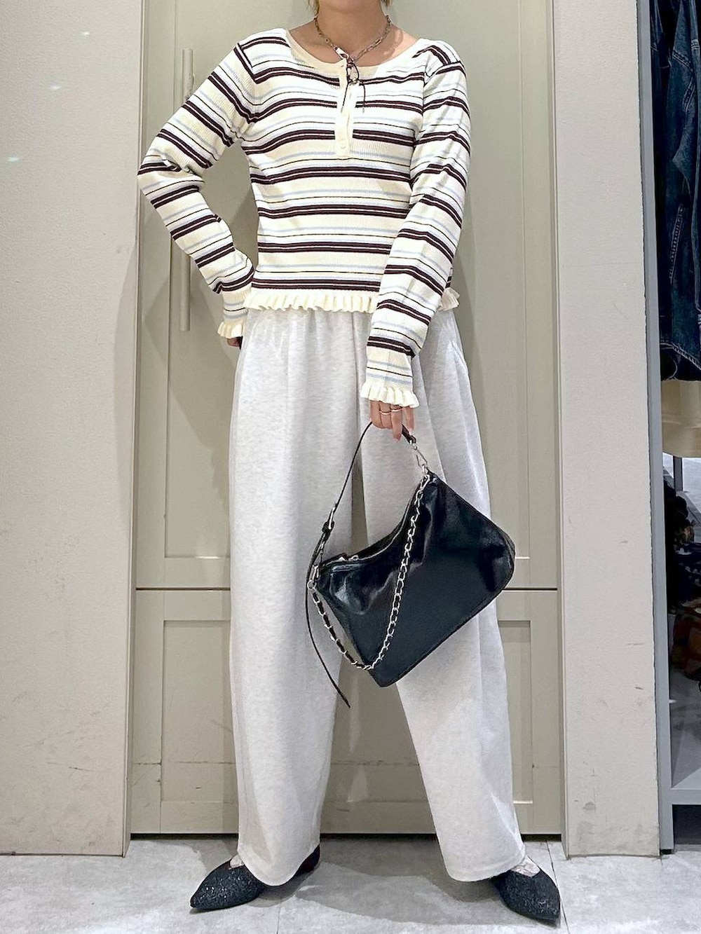 グレー系のスウェットパンツ、ブラック系のショルダーバッグ、ブラック系のパンプスを着用したレディースの冬コーディネートの4枚目の写真