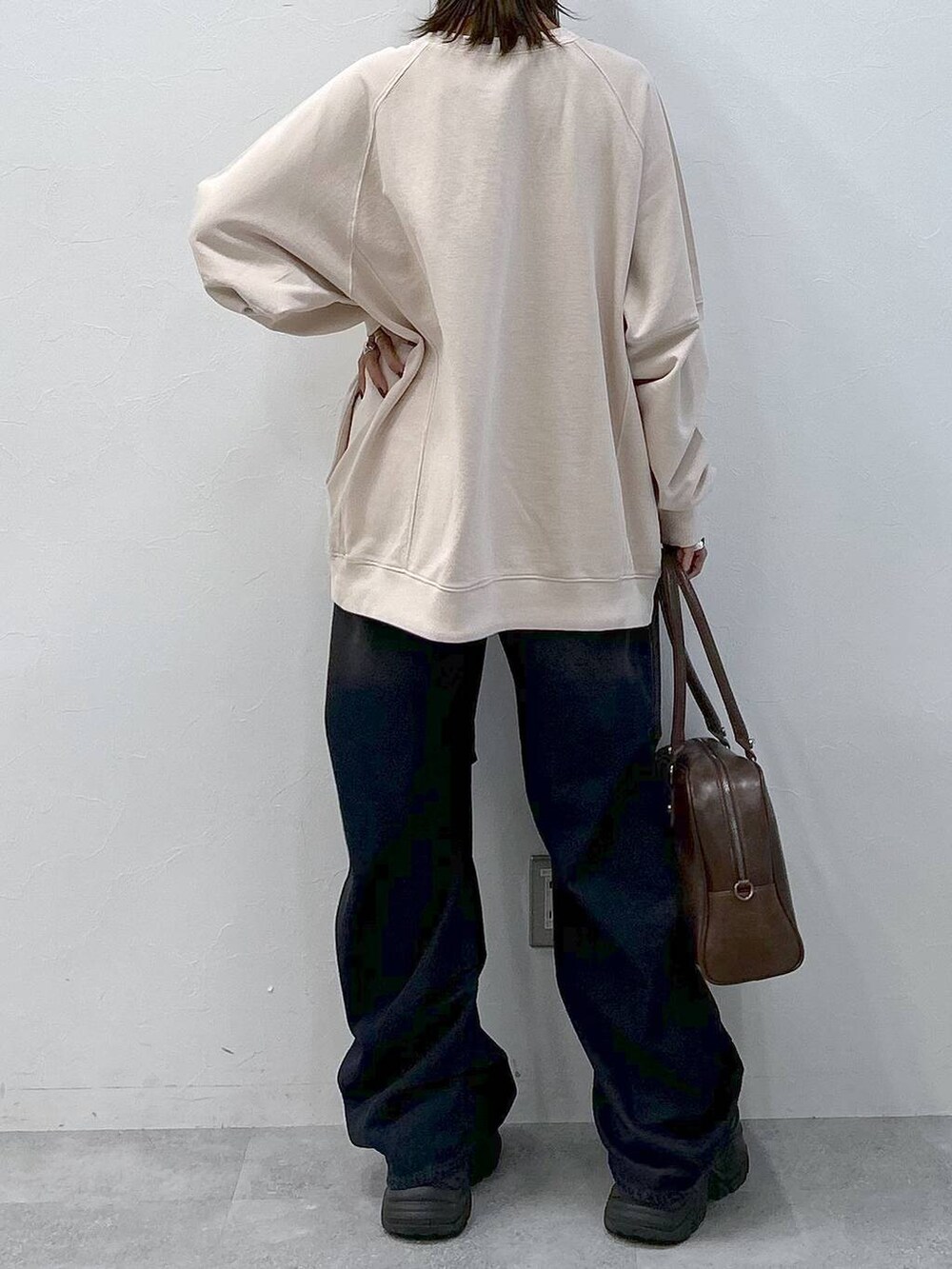 ブラック系のスニーカー、ブルー系のデニムパンツ、ブラウン系のボストンバッグを着用したレディースの冬コーディネートの6枚目の写真