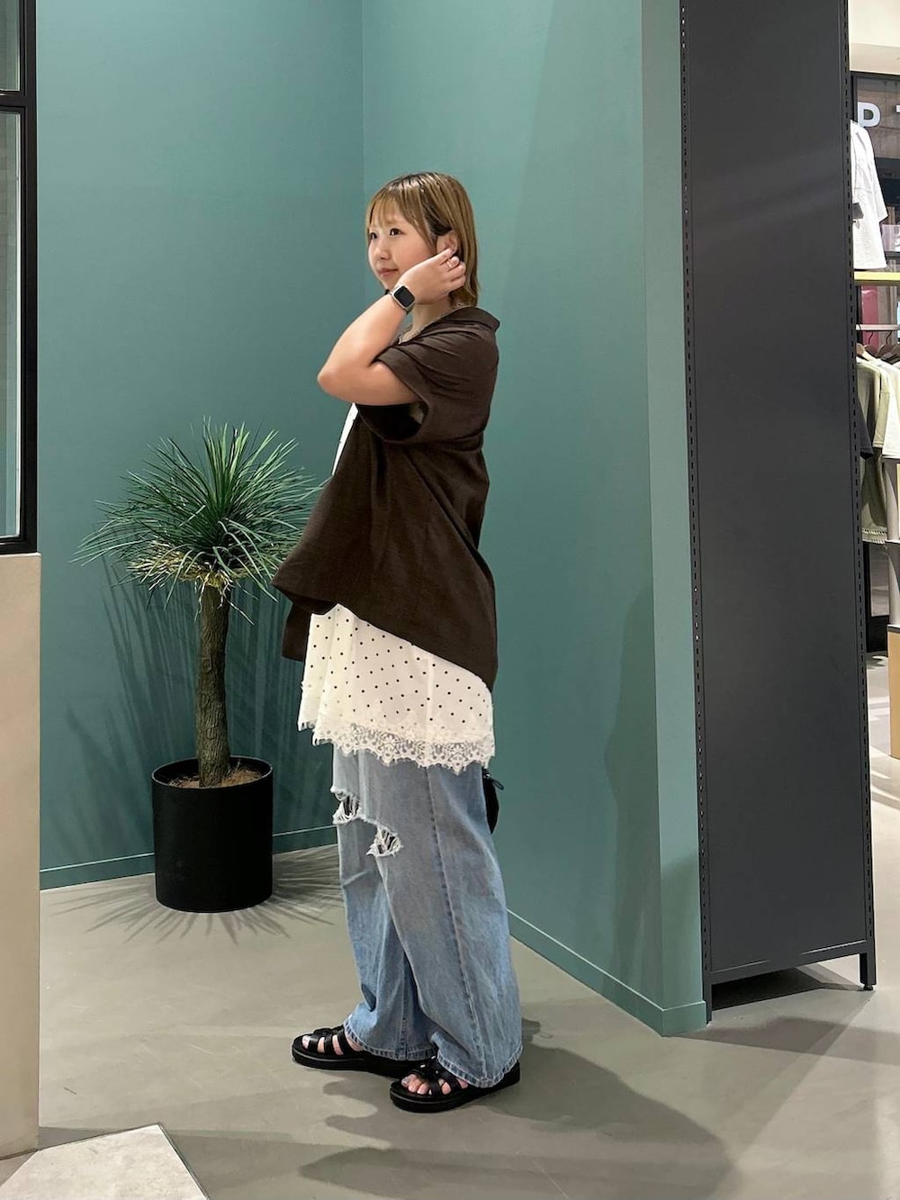 ブルー系のデニムパンツ、ブラウン系のテーラードジャケット、ブラック系のサンダルを着用したレディースの夏コーディネートの2枚目の写真