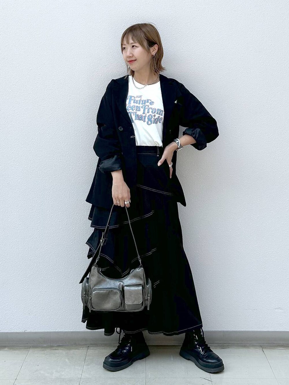 ブラック系のテーラードジャケット、ブラック系のブーツ、ベージュ系のTシャツ/カットソーを着用したレディースの秋コーディネートの7枚目の写真