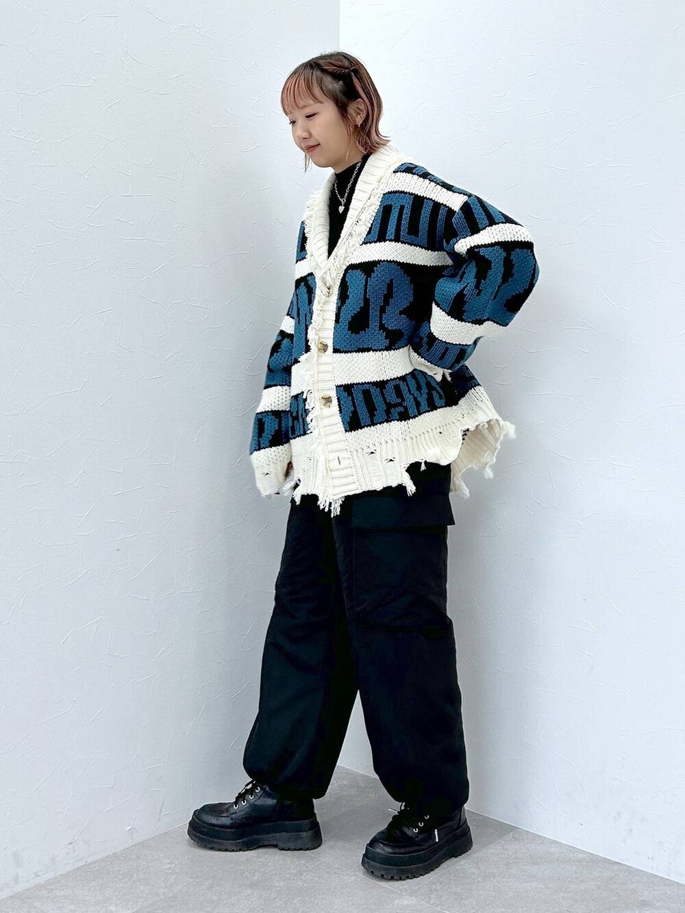 ブラック系のブーツ、ブラック系のニット/セーター、ブラック系のカーゴパンツを着用したレディースの冬コーディネートの2枚目の写真