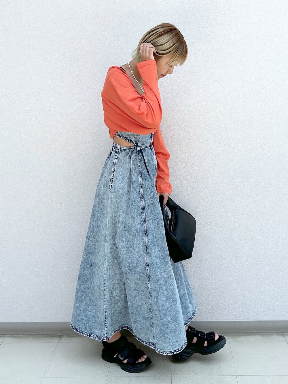 オレンジ系のカーディガン/ボレロ、ブルー系のジャンパースカートを着用したレディースの夏コーディネートの2枚目の写真