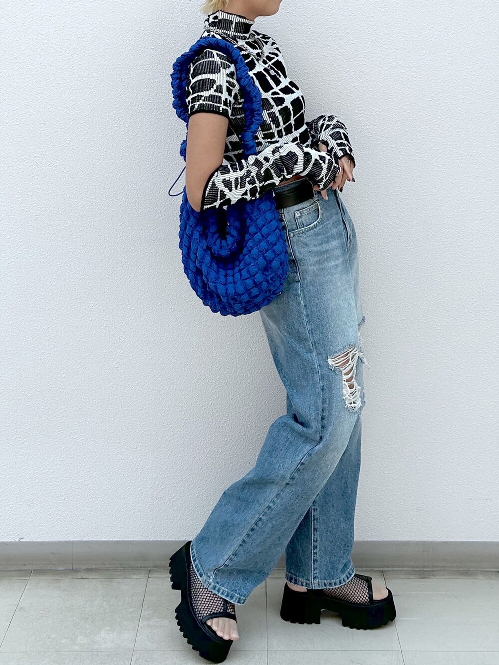 ブラック系のニット/セーター、ブルー系のデニムパンツ、ブラック系のサンダルを着用したレディースの夏コーディネートの5枚目の写真