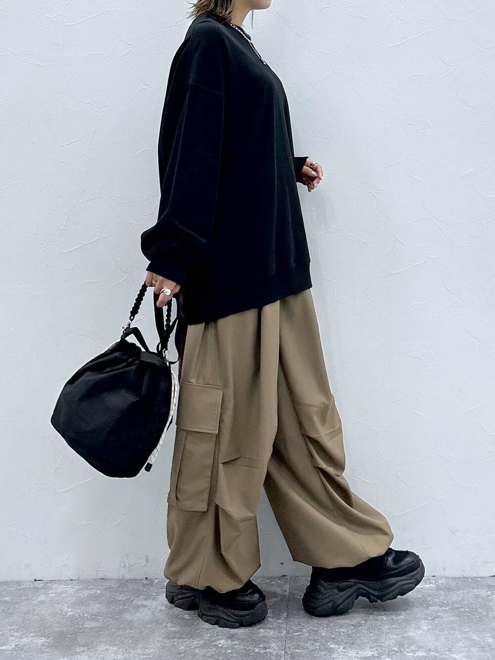 ブラック系のスニーカー、ブラック系のスウェット、ブラック系のショルダーバッグを着用したレディースの秋コーディネートの5枚目の写真