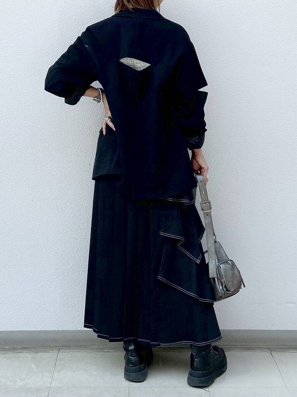 ブラック系のテーラードジャケット、ブラック系のブーツ、ベージュ系のTシャツ/カットソーを着用したレディースの秋コーディネートの6枚目の写真