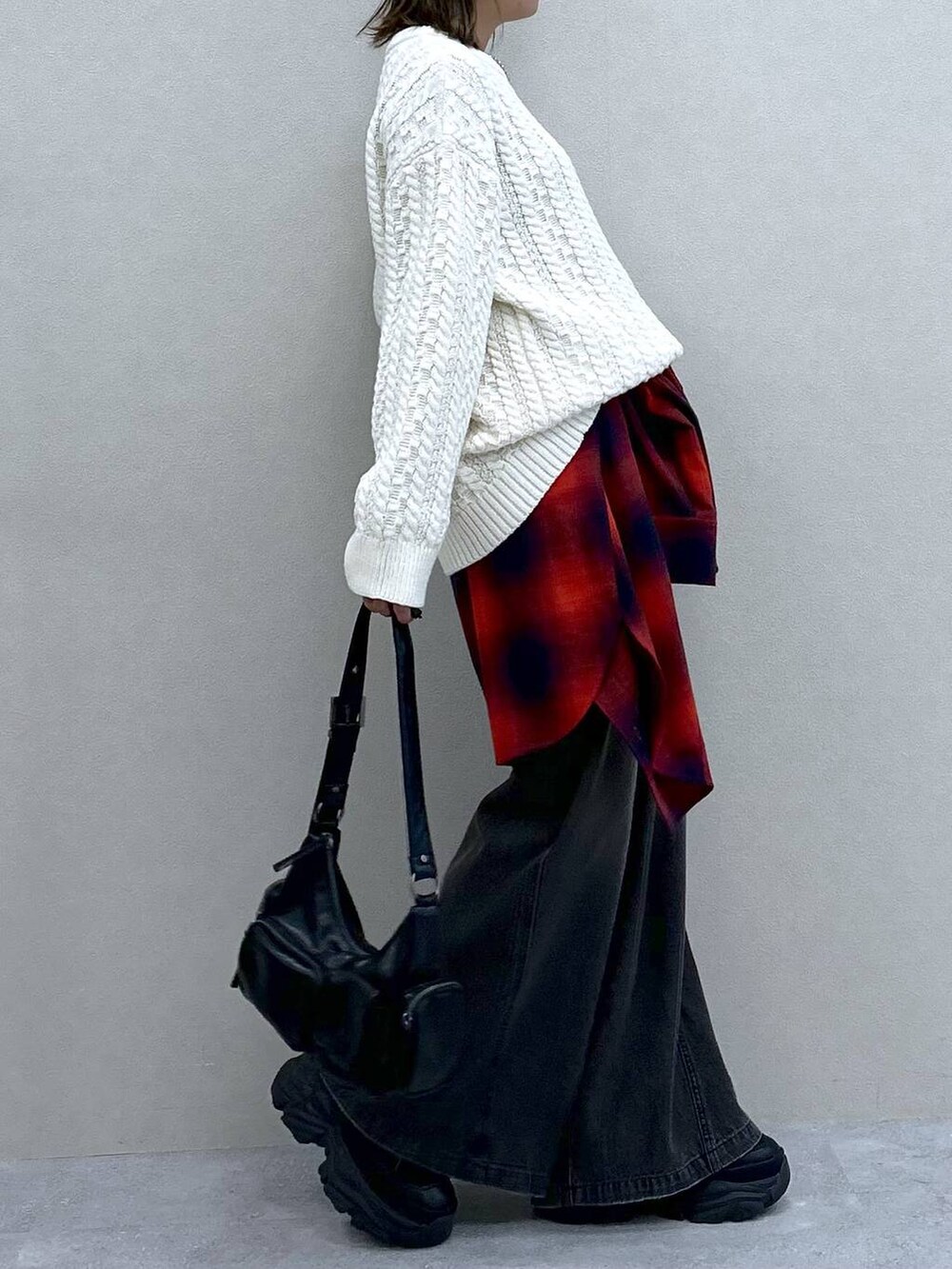 ブラック系のスニーカー、ブラック系のデニムパンツ、ブラック系のショルダーバッグを着用したレディースの冬コーディネートの5枚目の写真