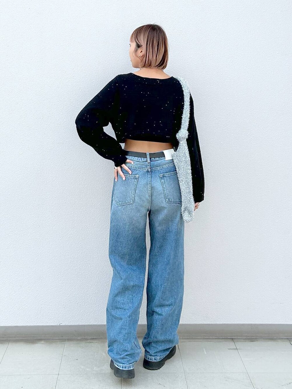 ブラック系のブーツ、ブルー系のデニムパンツ、シルバー系のトートバッグを着用したレディースの冬コーディネートの3枚目の写真