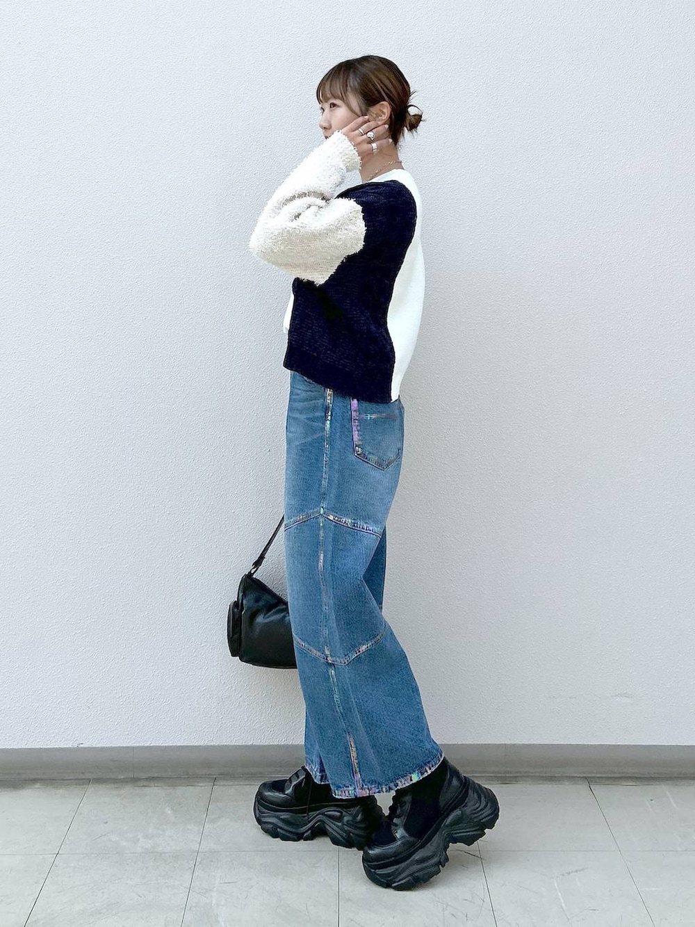 ブラック系のスニーカー、ブラック系のショルダーバッグ、ブルー系のデニムパンツを着用したレディースの冬コーディネートの2枚目の写真