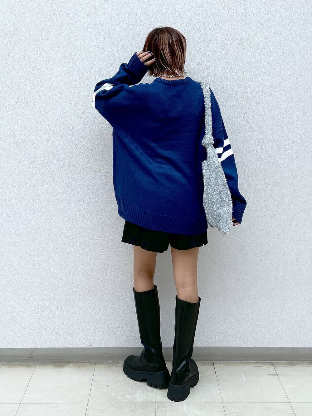 シルバー系のトートバッグ、ブラック系のブーツ、ブラック系のその他パンツを着用したレディースの秋コーディネートの3枚目の写真