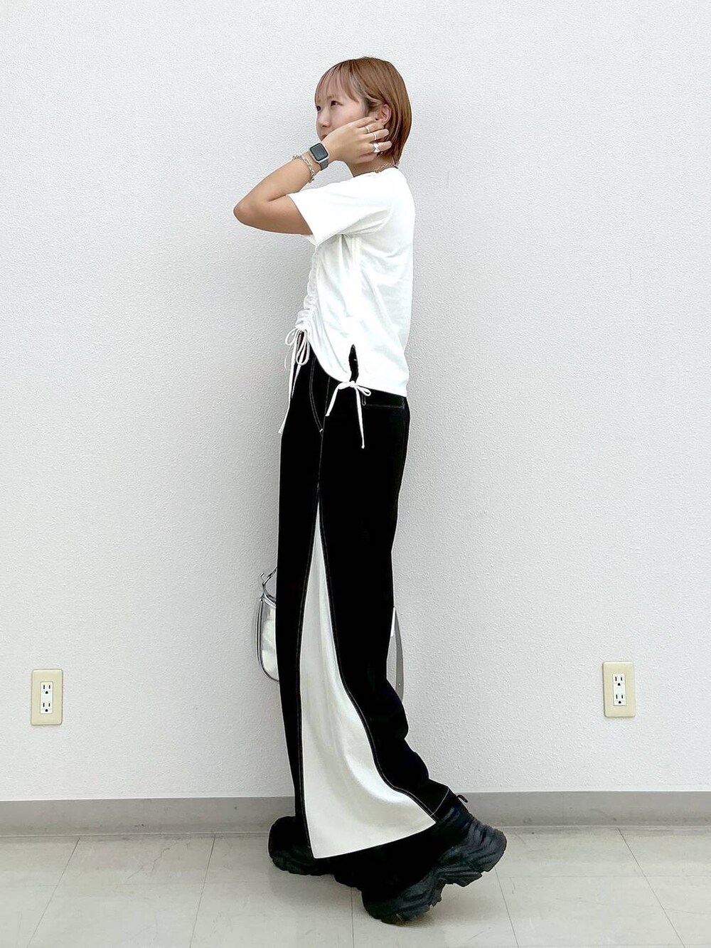 ブラック系のスニーカー、シルバー系のショルダーバッグ、ホワイト系のTシャツ/カットソーを着用したレディースの夏コーディネートの2枚目の写真