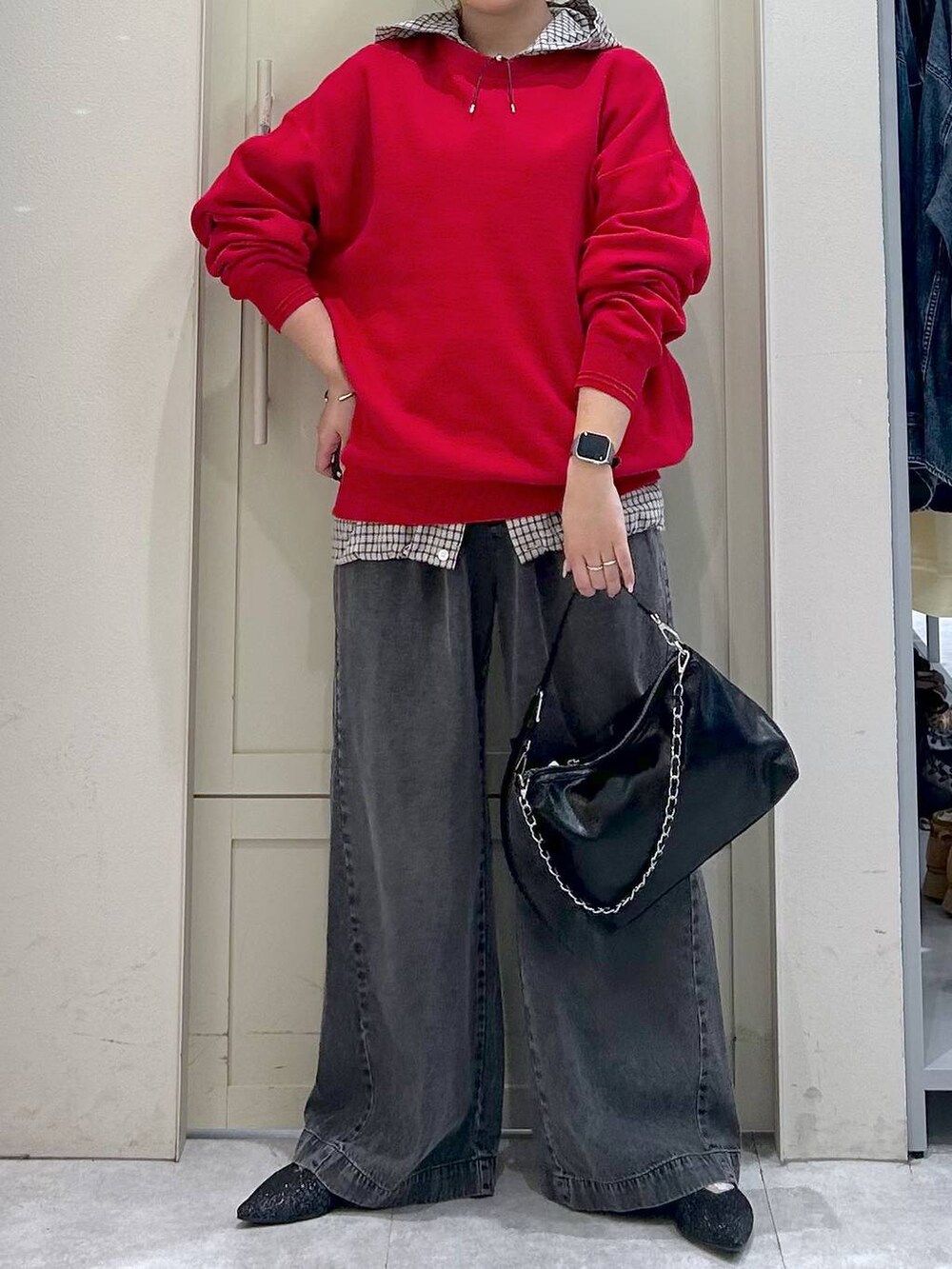 ブラック系のデニムパンツ、レッド系のニット/セーター、ブラック系のショルダーバッグを着用したレディースの春コーディネートの4枚目の写真