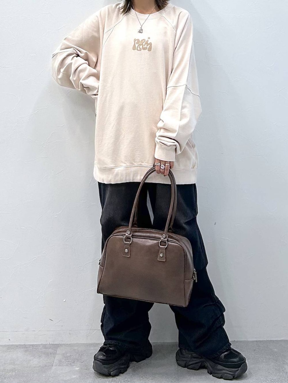 ブラック系のスニーカー、ブルー系のデニムパンツ、ブラウン系のボストンバッグを着用したレディースの冬コーディネートの4枚目の写真