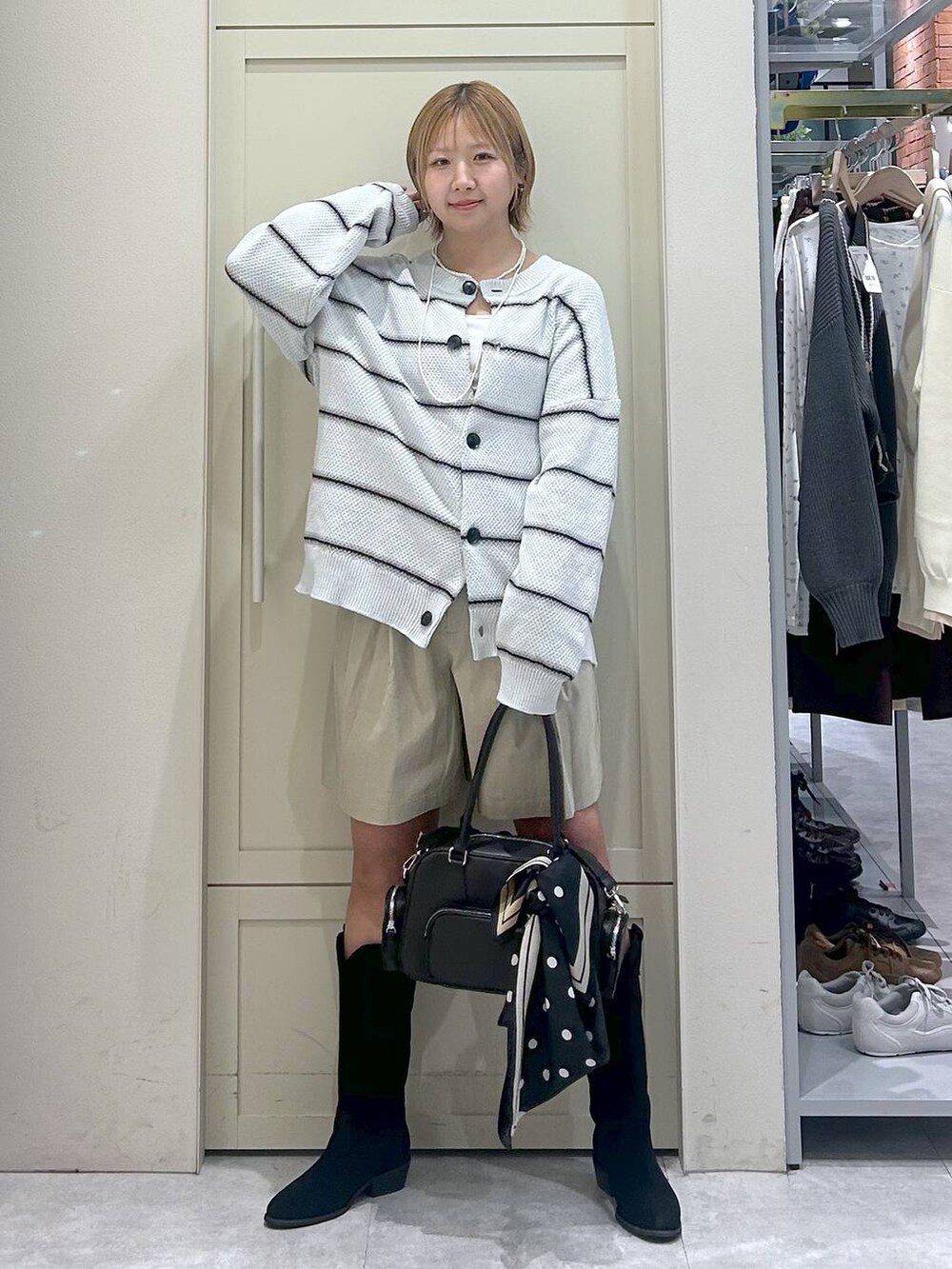 ホワイト系のキャミソール、ブラック系のブーツ、ブラック系のボストンバッグを着用したレディースの春コーディネートの6枚目の写真