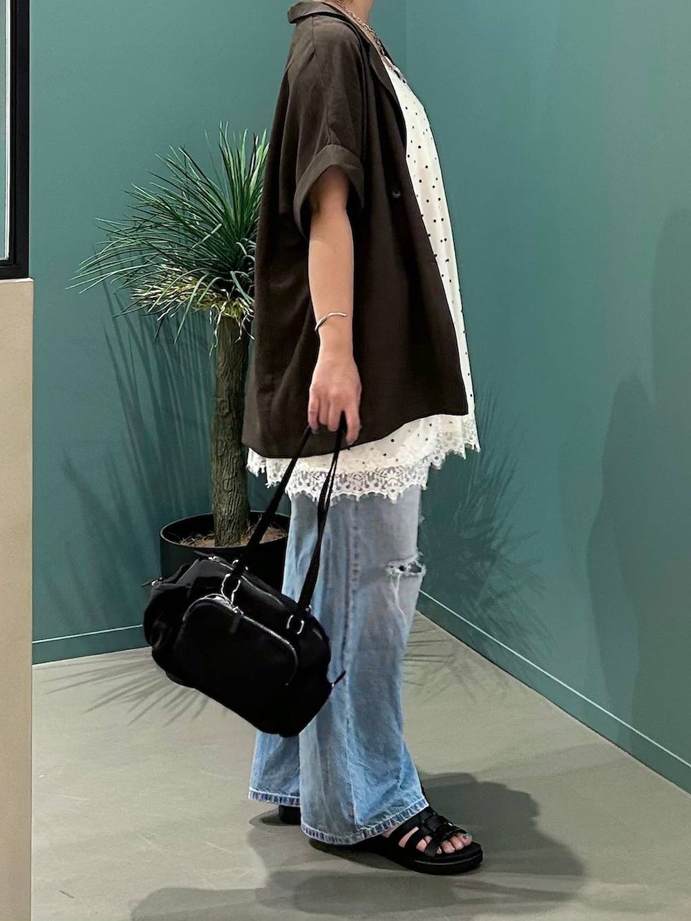 ブルー系のデニムパンツ、ブラウン系のテーラードジャケット、ブラック系のサンダルを着用したレディースの夏コーディネートの5枚目の写真