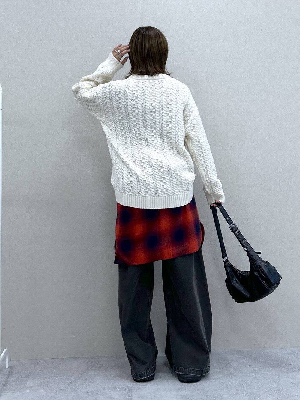 ブラック系のスニーカー、ブラック系のデニムパンツ、ブラック系のショルダーバッグを着用したレディースの冬コーディネートの3枚目の写真