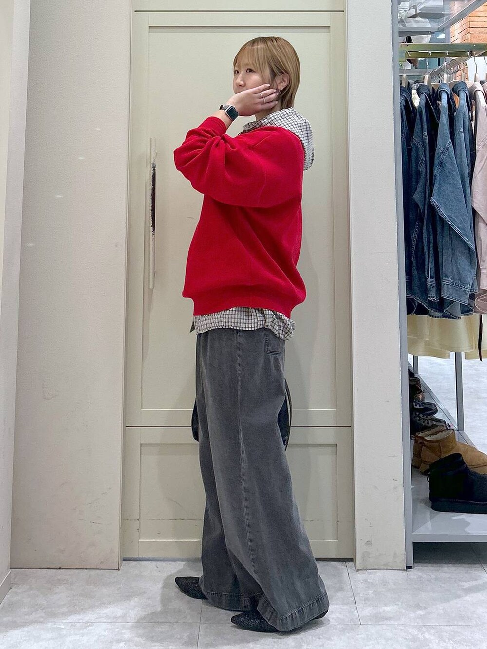 ブラック系のデニムパンツ、レッド系のニット/セーター、ブラック系のショルダーバッグを着用したレディースの春コーディネートの2枚目の写真