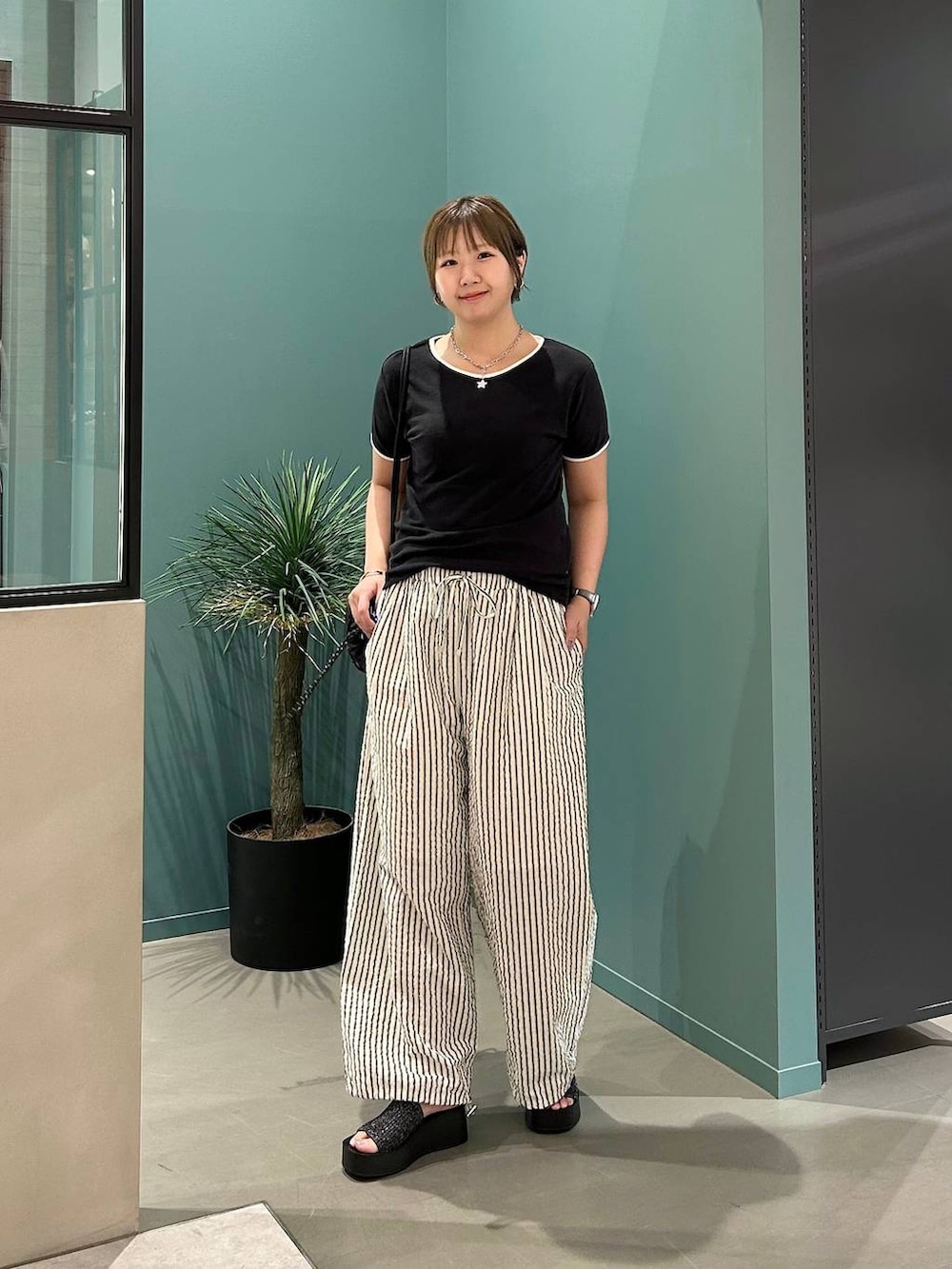 ブラック系のTシャツ/カットソー、ブラック系のサンダル、ブラック系のバックパック/リュックを着用したレディースの夏コーディネートの7枚目の写真