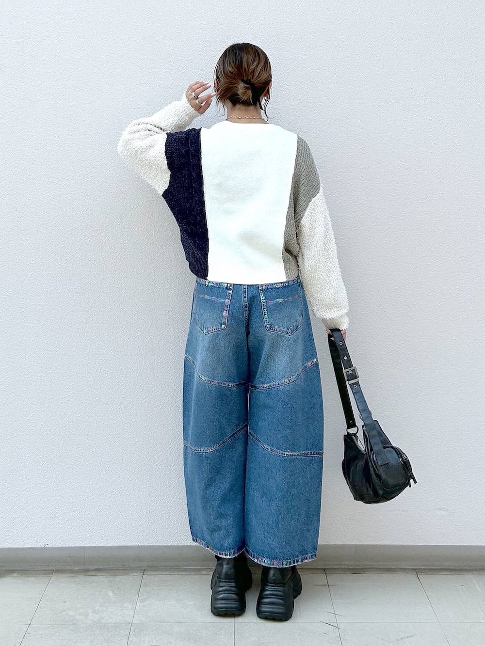 ブラック系のスニーカー、ブラック系のショルダーバッグ、ブルー系のデニムパンツを着用したレディースの冬コーディネートの3枚目の写真