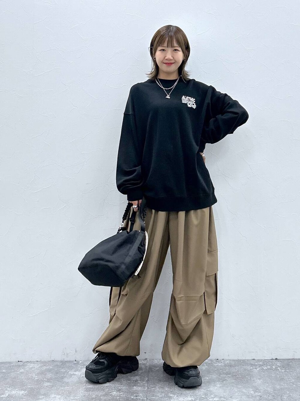 ブラック系のスニーカー、ブラック系のスウェット、ブラック系のショルダーバッグを着用したレディースの秋コーディネートの7枚目の写真