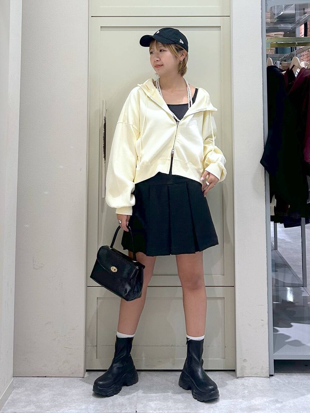 ブラック系のブーツ、ブラック系のボストンバッグ、グレー系のスカートを着用したレディースの秋コーディネートの7枚目の写真