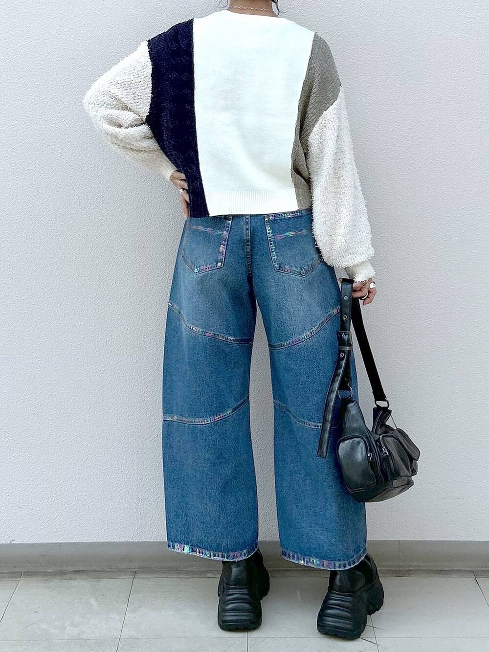 ブラック系のスニーカー、ブラック系のショルダーバッグ、ブルー系のデニムパンツを着用したレディースの冬コーディネートの6枚目の写真