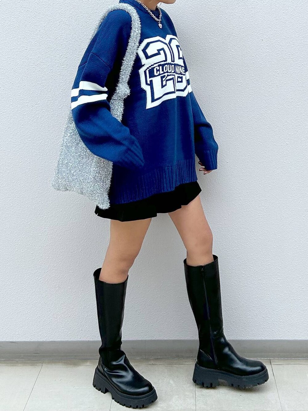 シルバー系のトートバッグ、ブラック系のブーツ、ブラック系のその他パンツを着用したレディースの秋コーディネートの5枚目の写真