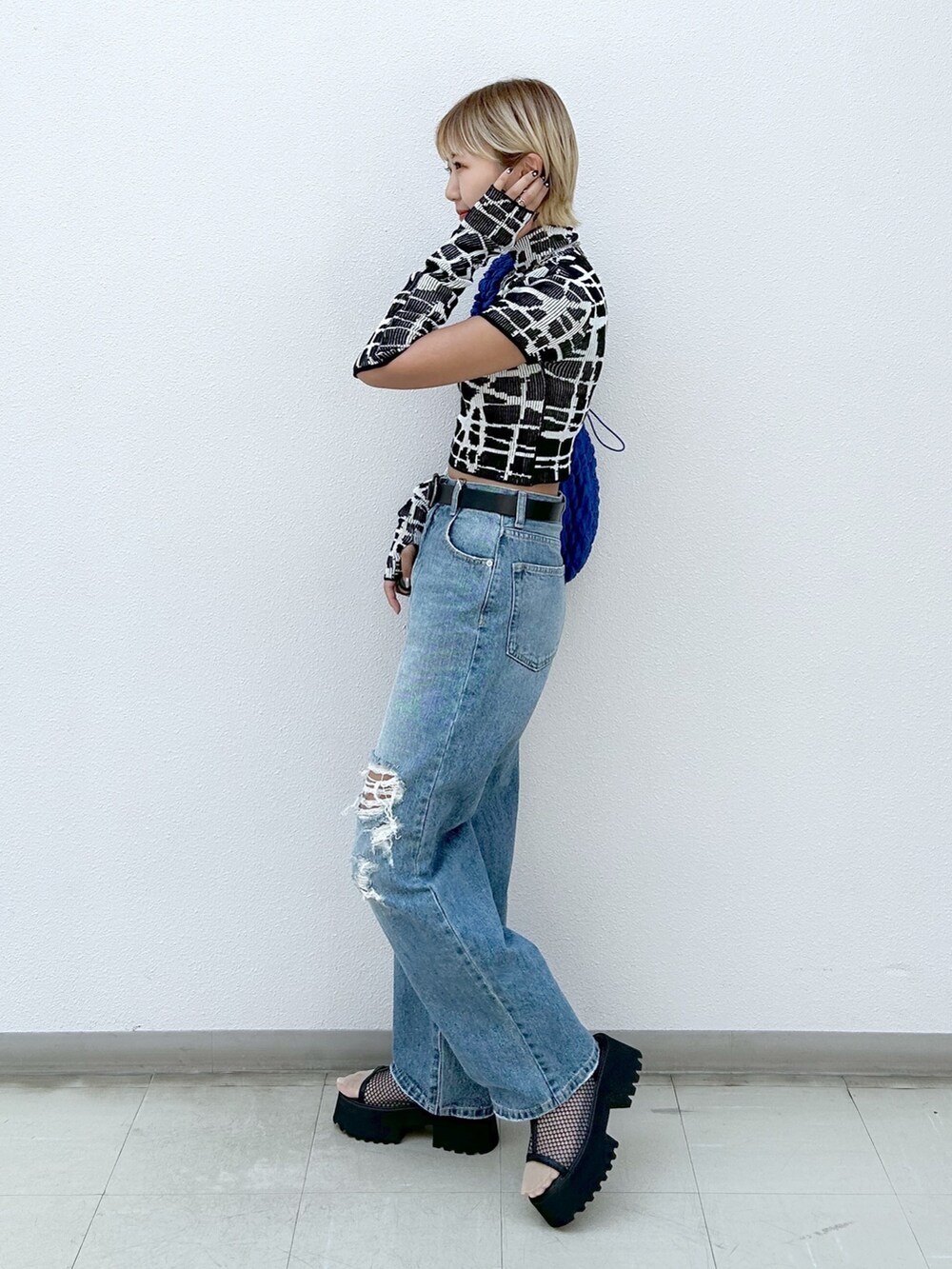 ブラック系のニット/セーター、ブルー系のデニムパンツ、ブラック系のサンダルを着用したレディースの夏コーディネートの2枚目の写真