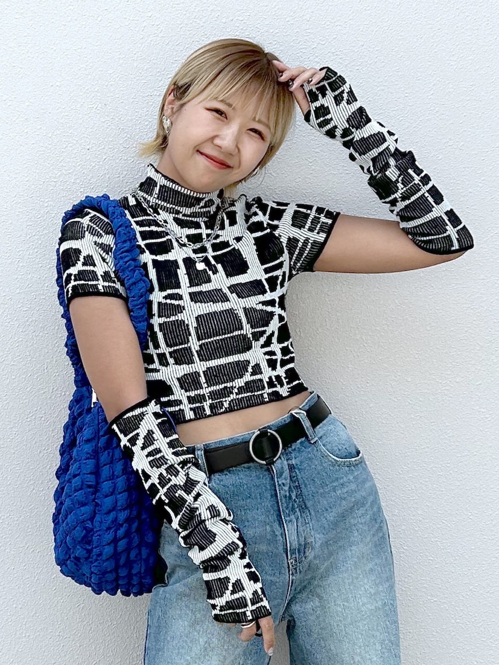 ブラック系のニット/セーター、ブルー系のデニムパンツ、ブラック系のサンダルを着用したレディースの夏コーディネートの4枚目の写真