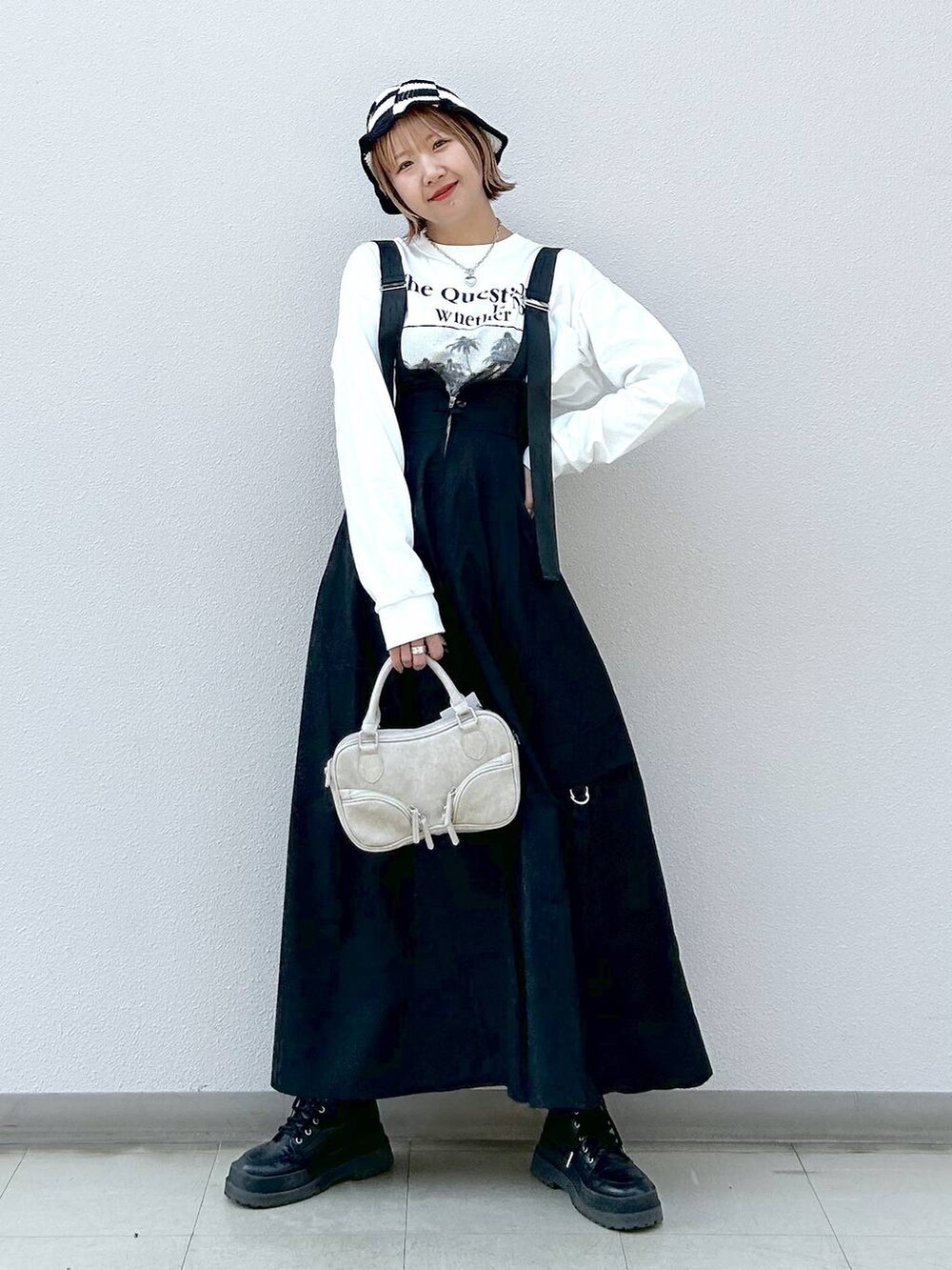 ホワイト系のTシャツ/カットソー、ブラック系のブーツ、ブラック系のジャンパースカートを着用したレディースの冬コーディネートの6枚目の写真