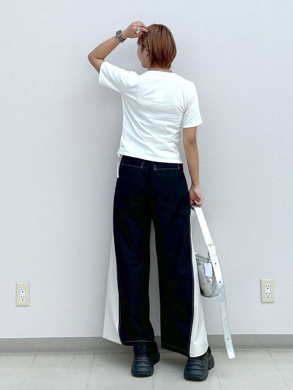 ブラック系のスニーカー、シルバー系のショルダーバッグ、ホワイト系のTシャツ/カットソーを着用したレディースの夏コーディネートの3枚目の写真