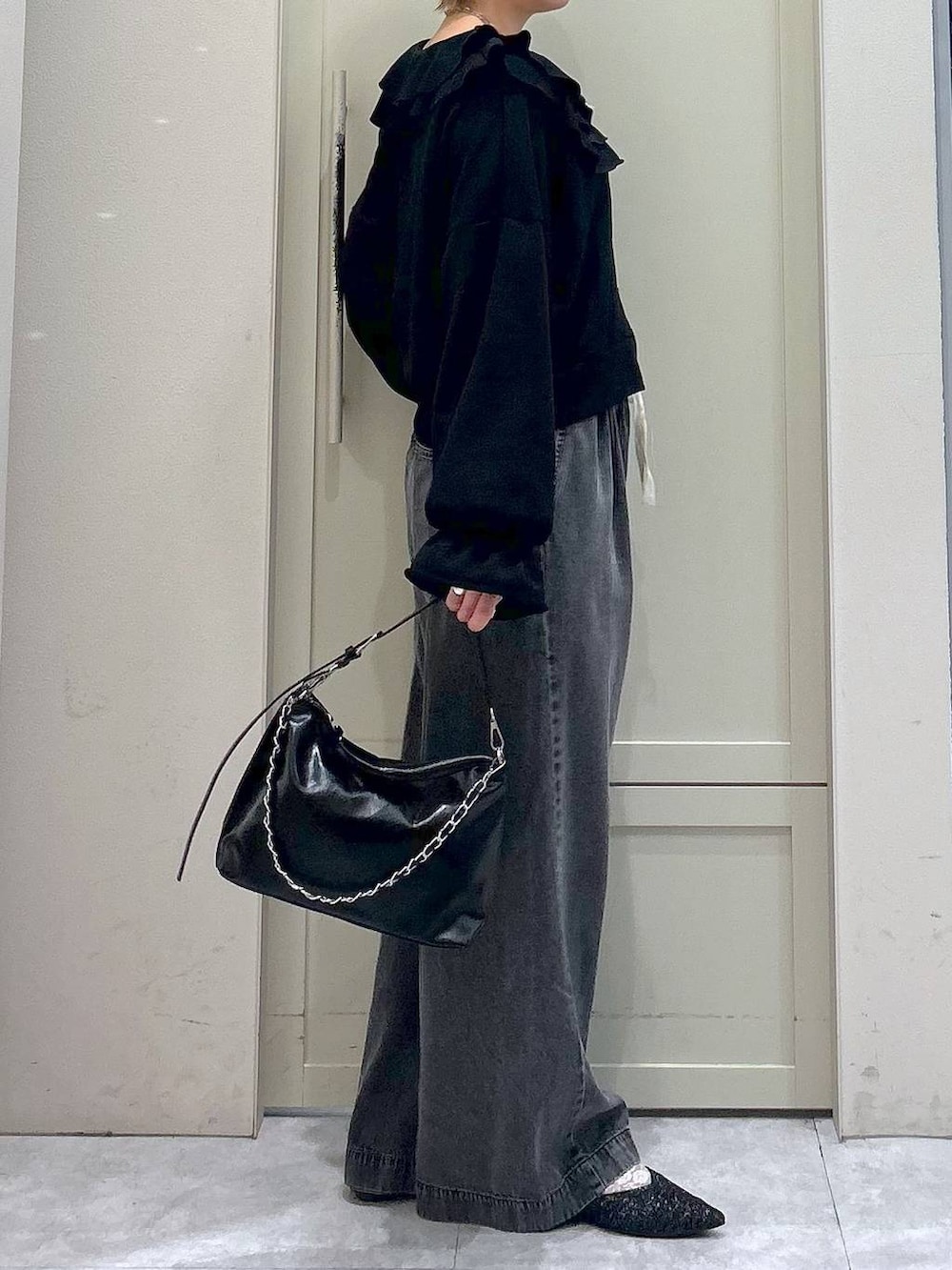 ブラック系のデニムパンツ、ブラック系のショルダーバッグ、ブラック系のパンプスを着用したレディースの冬コーディネートの5枚目の写真