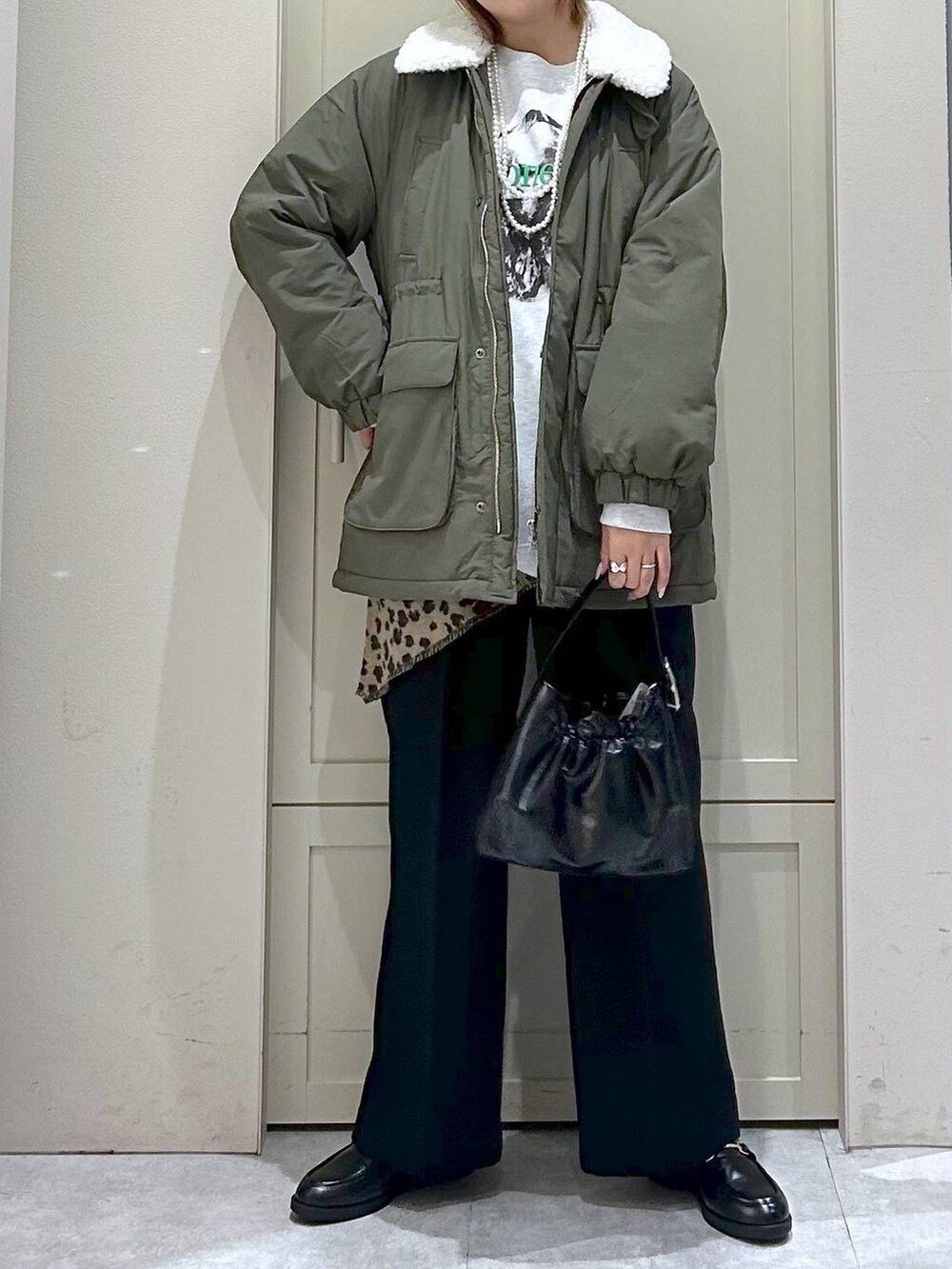 ブラック系のスラックス、グリーン系のその他アウター、ブラック系のローファーを着用したレディースの冬コーディネートの4枚目の写真