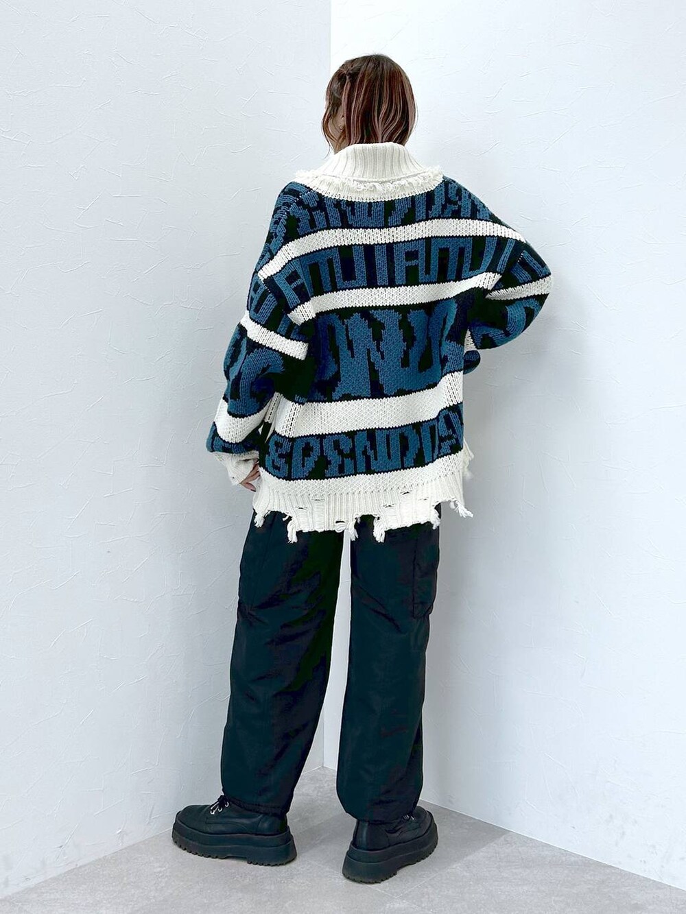 ブラック系のブーツ、ブラック系のニット/セーター、ブラック系のカーゴパンツを着用したレディースの冬コーディネートの3枚目の写真