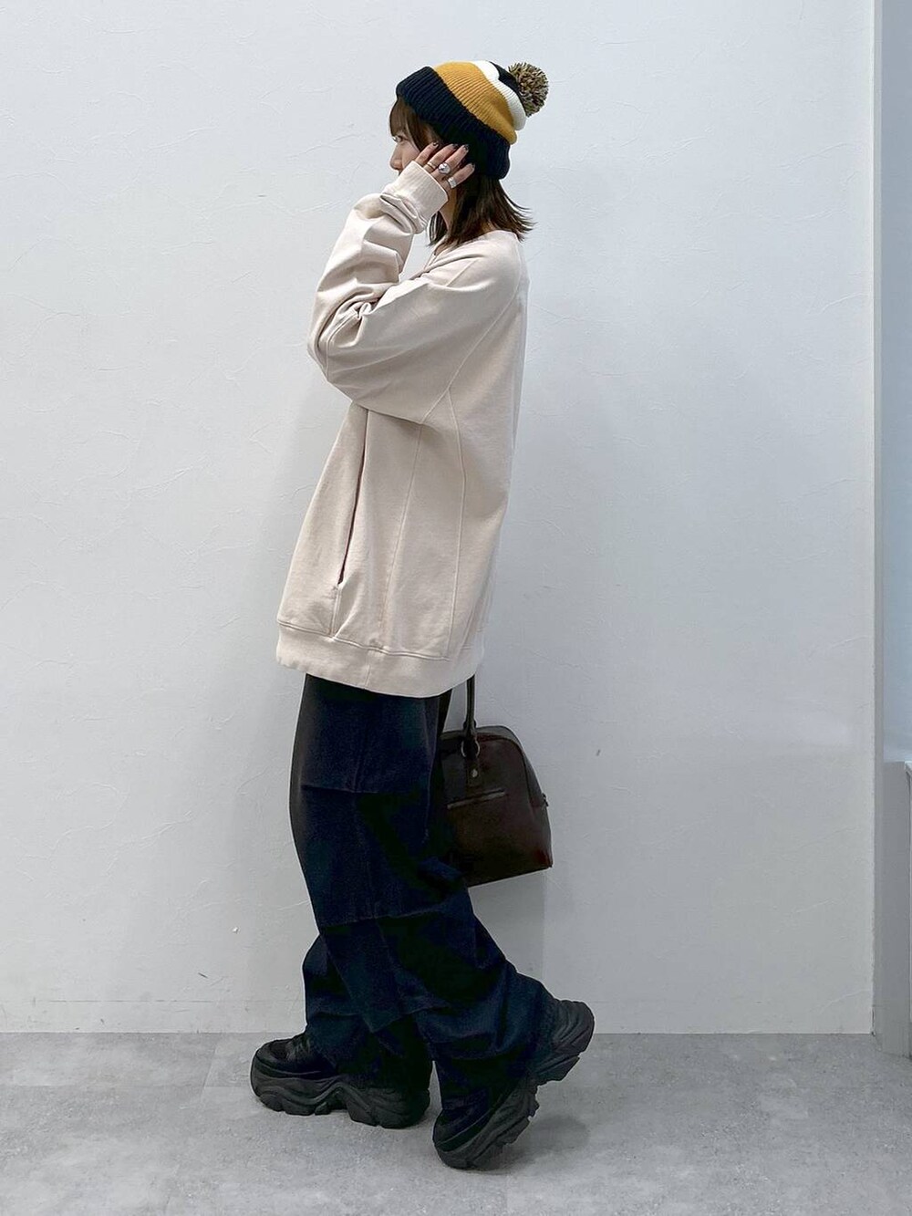 ブラック系のスニーカー、ブルー系のデニムパンツ、ブラウン系のボストンバッグを着用したレディースの冬コーディネートの2枚目の写真