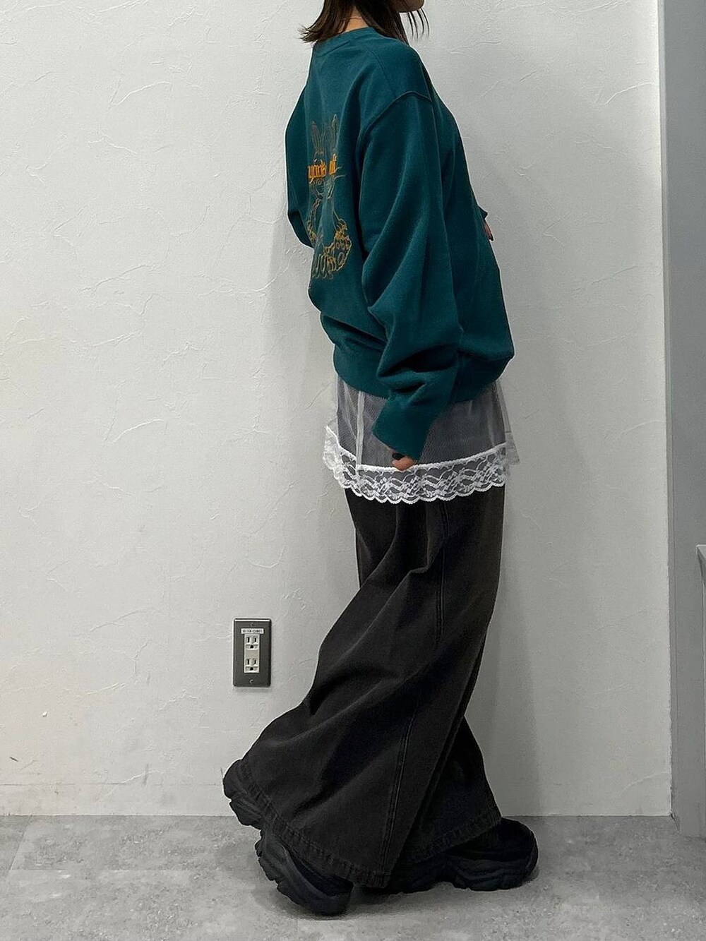 ブラック系のスニーカー、ブラック系のデニムパンツ、グリーン系のスウェットを着用したレディースの冬コーディネートの5枚目の写真