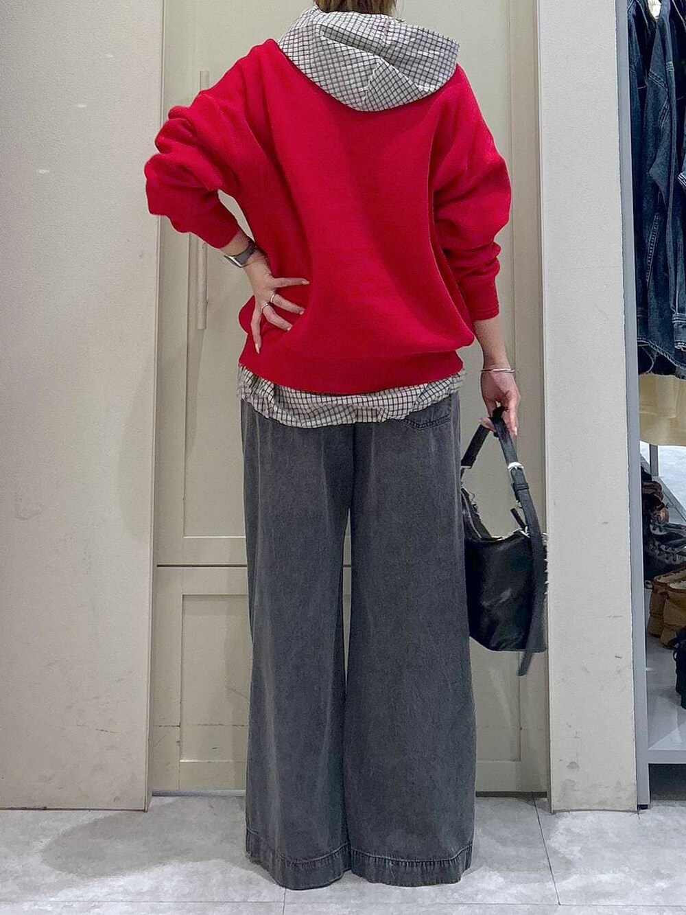 ブラック系のデニムパンツ、レッド系のニット/セーター、ブラック系のショルダーバッグを着用したレディースの春コーディネートの6枚目の写真